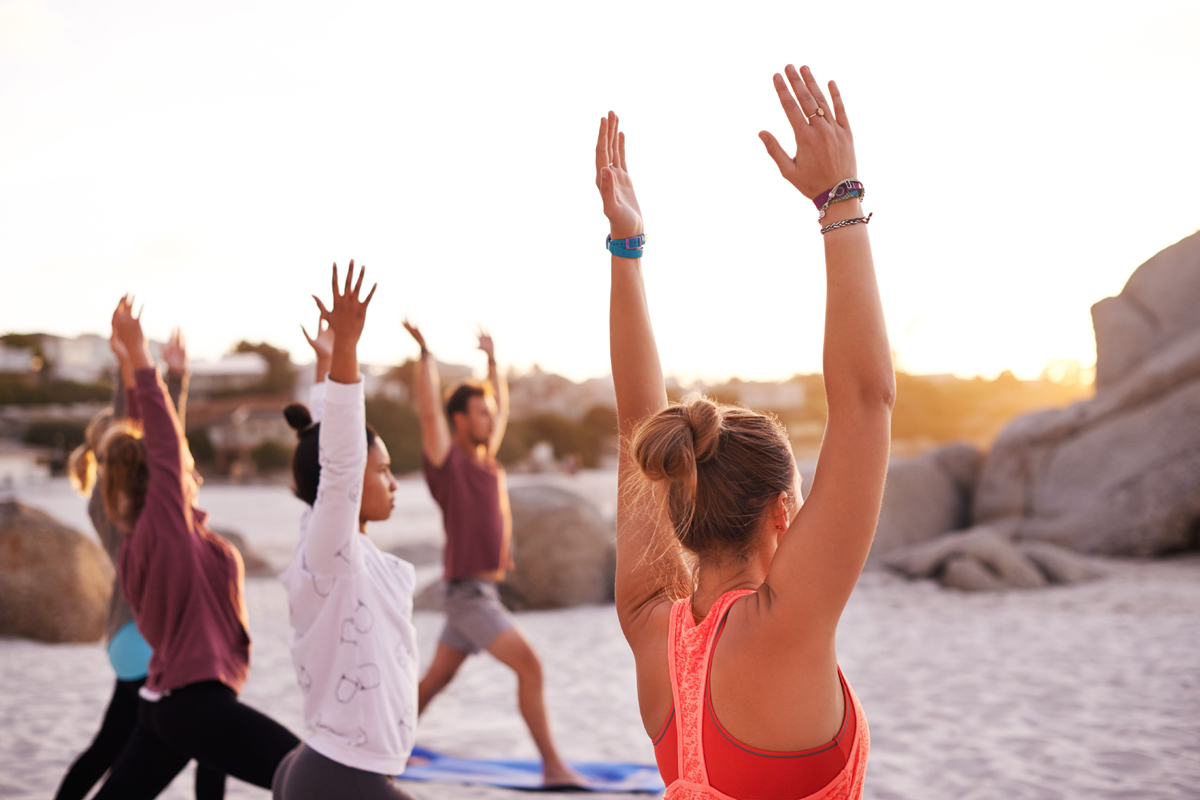 Fitness instructors teaching a yoga class at the beach on vacation